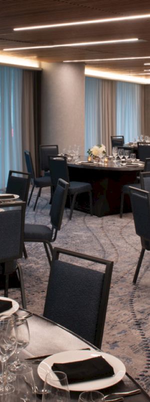 A banquet room with elegantly set round tables, blue chairs, and soft lighting.