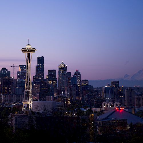Seattle skyline at dusk with the Space Needle prominently featured and Mount Rainier visible in the background.
